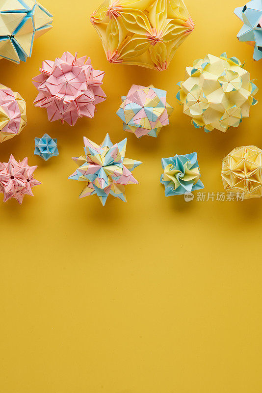 Set的multicolorÂ手工制作modularÂ折纸球或Kusudama孤立在黄色背景。视觉艺术，几何学，折纸艺术，纸工艺品。俯视图，特写，选择性聚焦，复制空间。