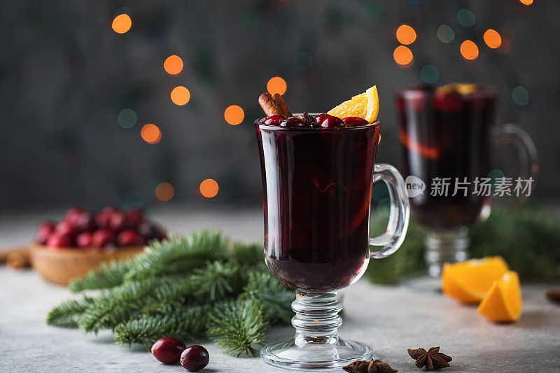 在圣诞背景下，用自制的热葡萄酒酒杯，点缀着圣诞树、蔓越莓和散景。