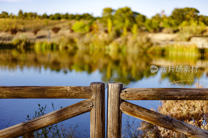 秋天日落时湖周围的木栅栏。自然环境。Presillas自然公园。Alcorcon,马德里,西班牙。