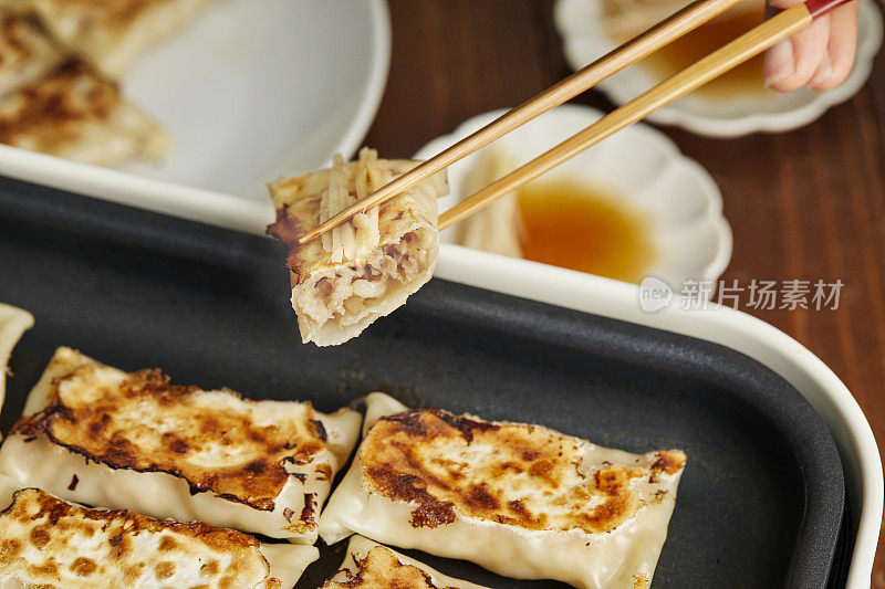 用筷子夹饺子的手。