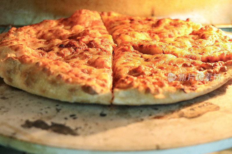 自制的玛格丽塔披萨在烤箱里烘烤，在披萨石头上烤脆的基底，磨碎的马苏里拉芝士，重点在前景