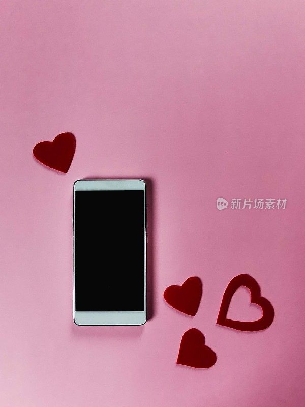 在粉红色的背景上，用毛毡做成的红心，智能手机的空白屏幕，空白的复制空间，一个模型的创意
