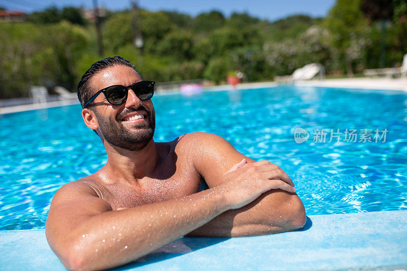 一个皮肤黝黑的英俊男子在泳池边玩得很开心