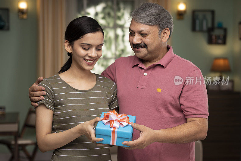 年幼的女儿在父亲节和他的生日给父亲一个礼盒，库存照片
