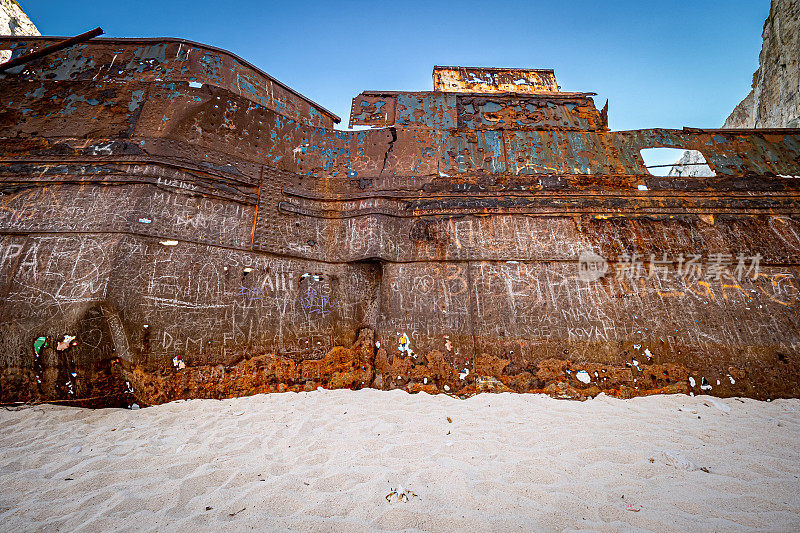 在希腊扎金索斯岛的纳瓦吉奥(走私者湾)海滩上，被高高的悬崖包围着的生锈的旧船残骸的奇妙景象