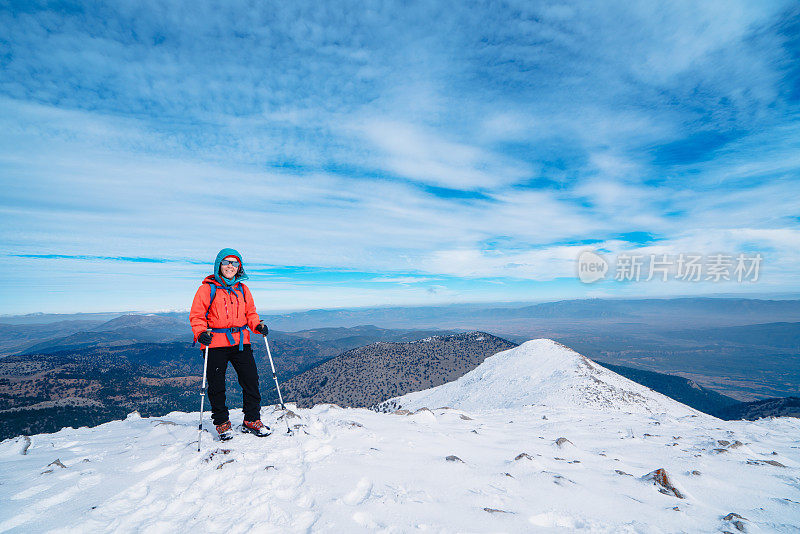 图为，登山成功的女登山者在雪山的山顶上正盯着相机