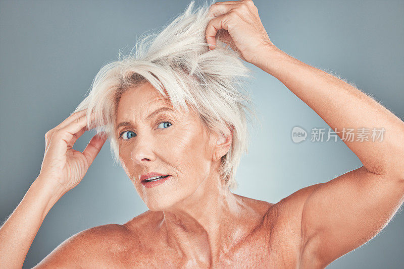 年长的女性，头发凌乱，对沙龙护理、化妆品或在灰色工作室背景下剪头发有压力。老年女性的肖像有一个糟糕的头发一天寻找改造或美容治疗