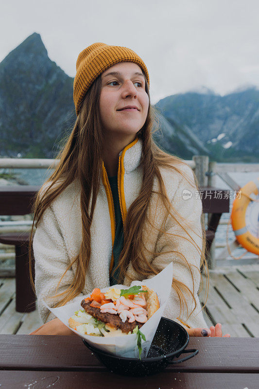 一位戴着黄色帽子的妇女在罗浮敦群岛享受美味的海鲜大餐