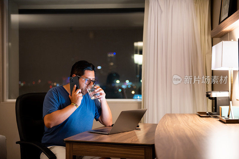一名男子晚上在酒店房间用手机聊天