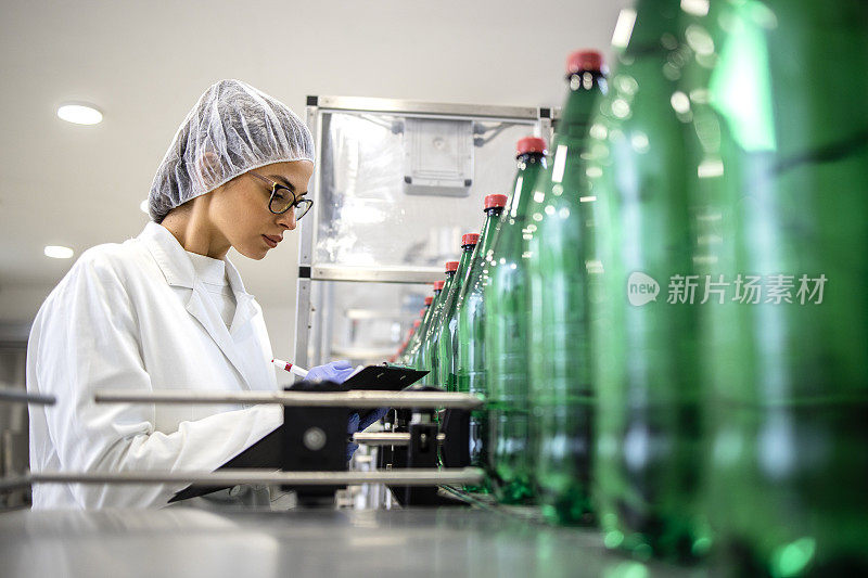 在PET装瓶厂工作的女性技术员，控制饮用水的生产和包装。