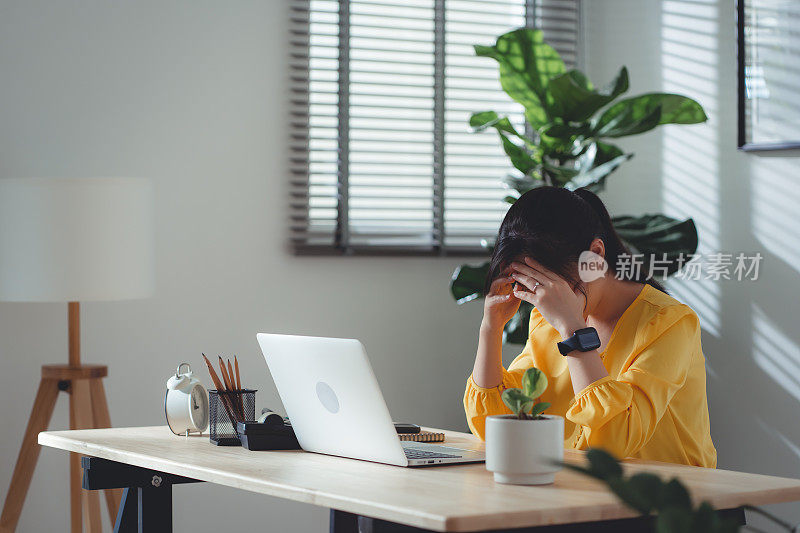 亚洲女性坐在家里头疼。