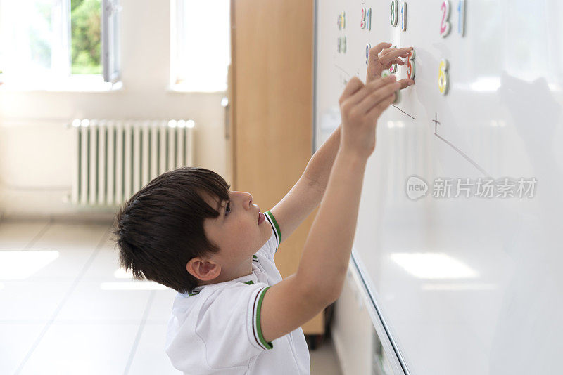 小学生穿着校服用白板上的磁性数字解数学题。