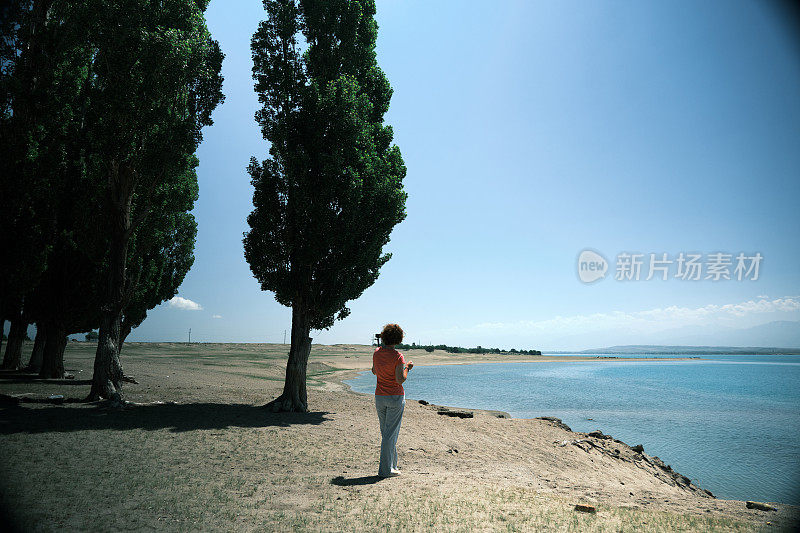 微笑的成熟女人正在海岸线上拍视频