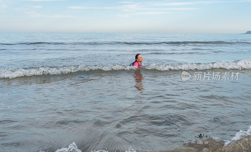 7岁的白种人女孩在海里游泳并溅起水花。在沙滩上休息，感受一下激情的飞溅。