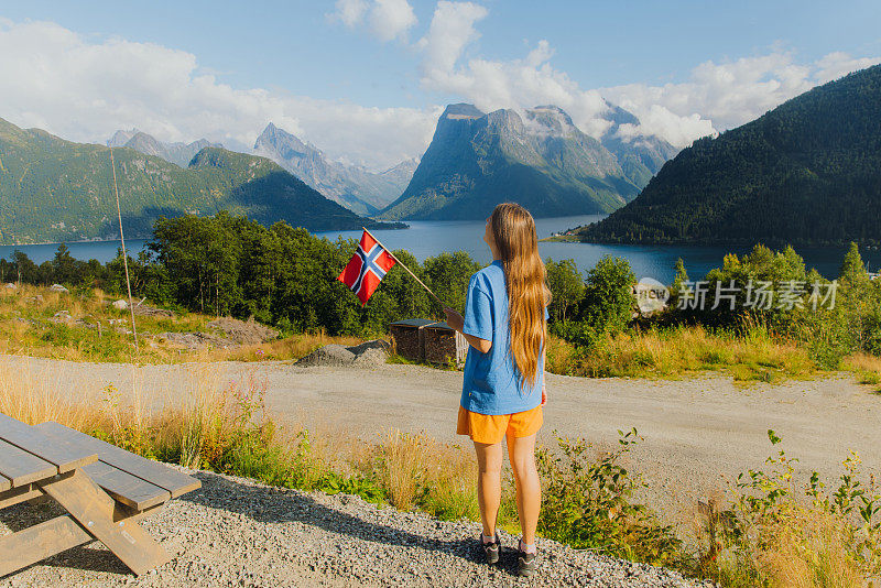 手持挪威国旗的女游客可以看到阿尔卑斯山山的美景