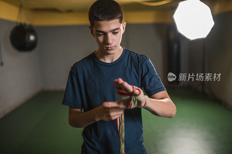 一名男运动员在拳击馆里开始训练前，在手上缠上防护绷带