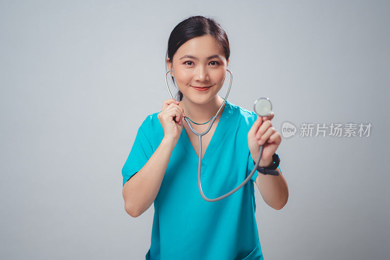 穿着医生制服的亚洲妇女医生开心地微笑着拿着听诊器孤立在白色背景。