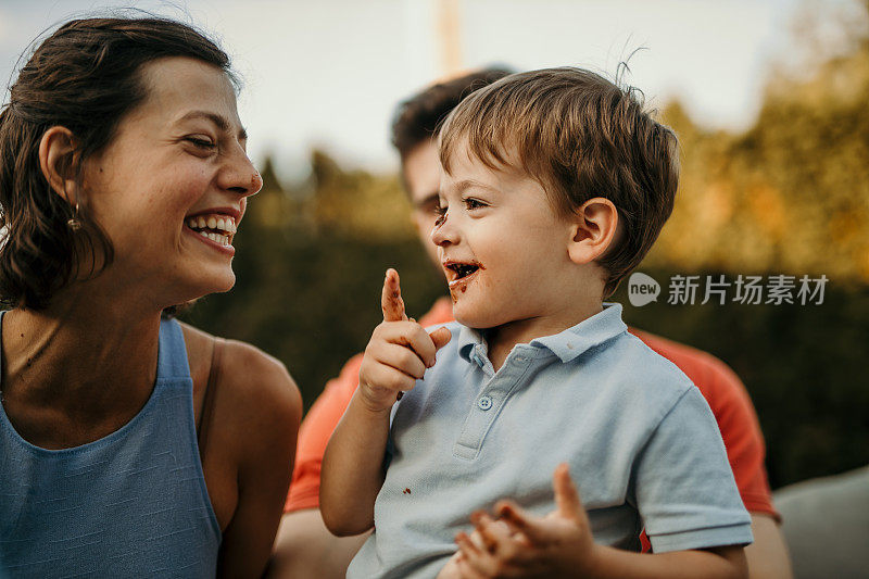 一个温馨的家庭庆祝活动在美丽的花园中展开，有美味的生日蛋糕和聚会桌，周围是大自然的壮丽户外