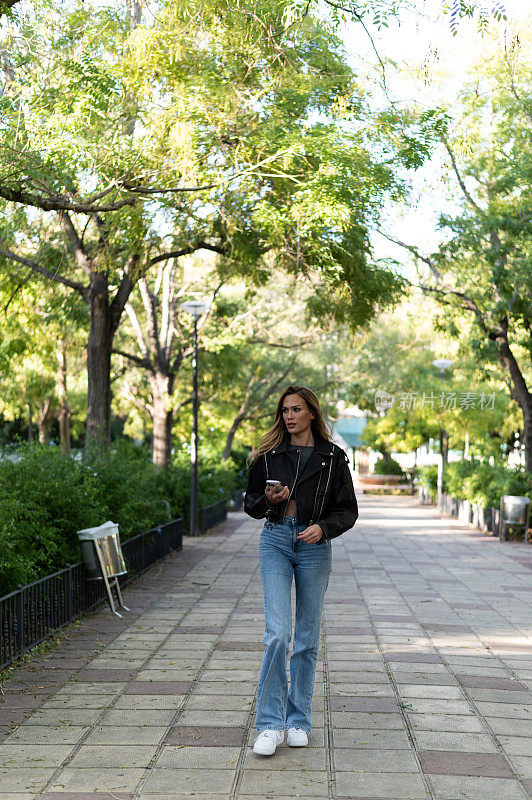 一个金发女人在城市公园边走边打电话