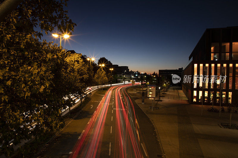 日落时繁忙街道的未来主义镜头，在黑暗中经过罗伊特林根市政厅