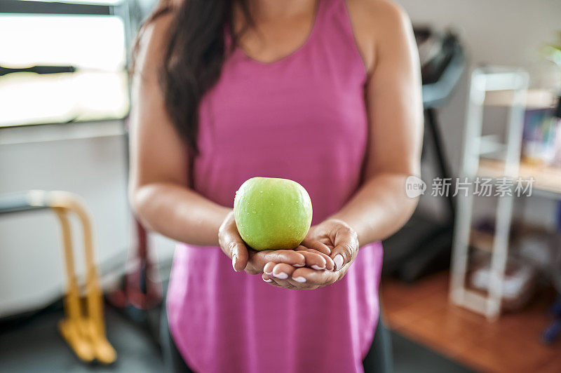 一个女人在家庭健身房拿着青苹果的特写