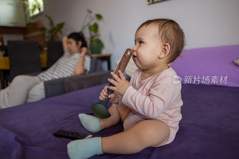 顽皮的白人女婴坐在床上玩勺子