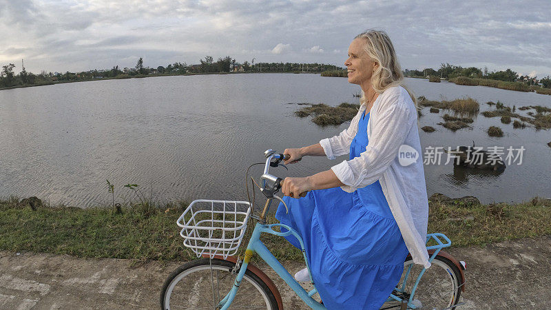 成熟的女人骑着自行车穿过稻田