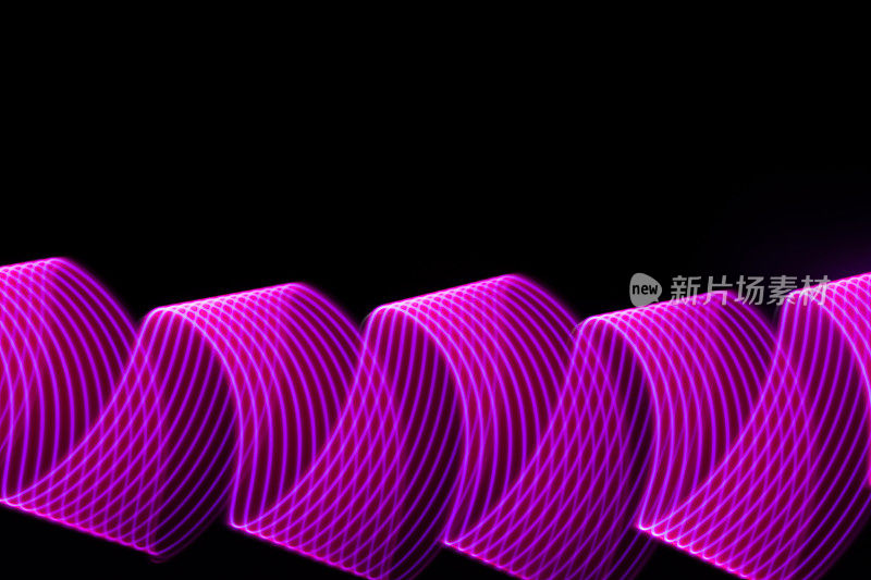粉红色，紫色的霓虹波的光卷曲与条纹在黑色的背景。抽象的背景，动感的线条，灯光绘画，现代风格的灯光效果。