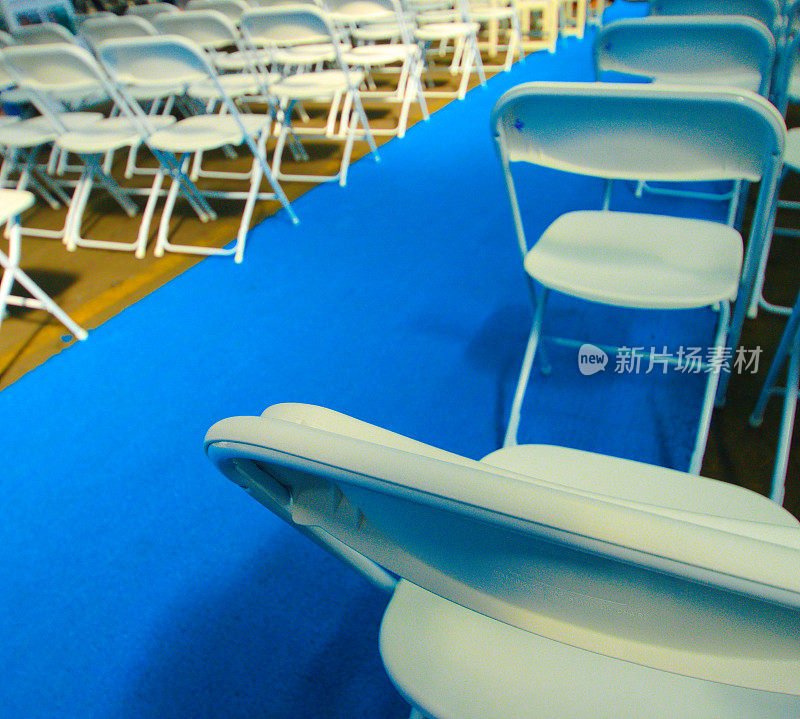 白色折叠椅排成一排，上面有蓝色的折叠椅，用于婚礼、毕业典礼或剪彩等场合