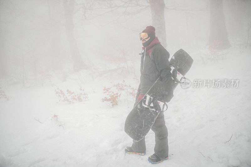 男子单板滑雪运动员准备在山上滑雪的全长视图