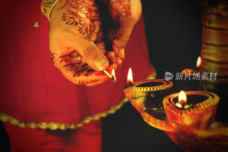 在排灯节、杜尔加普加节、卡尔瓦乔斯节或就职典礼等节日仪式上，一名妇女点燃灯笼或陶瓦灯的手的特写