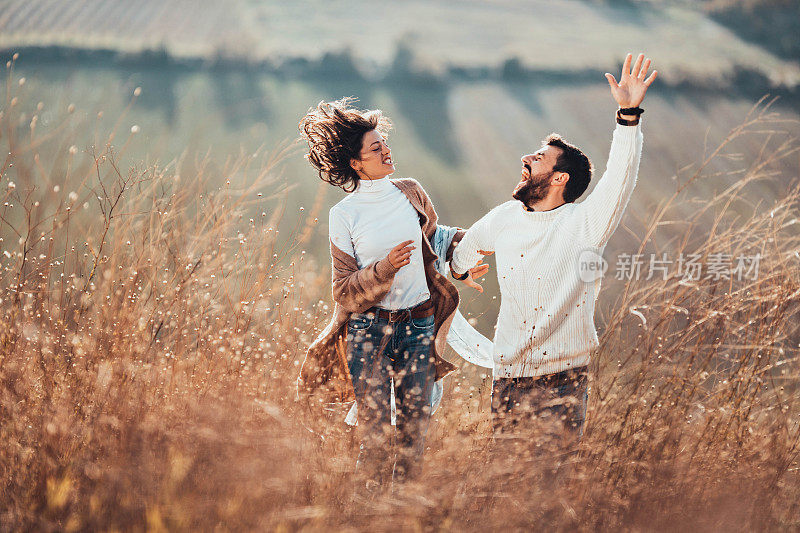 秋日里，快乐的情侣在高高的草丛中奔跑。