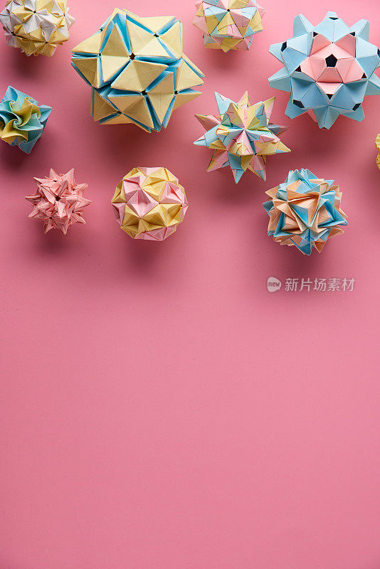 Set的multicolorÂ手工制作modularÂ折纸球或Kusudama孤立在粉红色的背景。视觉艺术，几何学，折纸艺术，纸工艺品。俯视图，特写，选择性聚焦，复制空间。