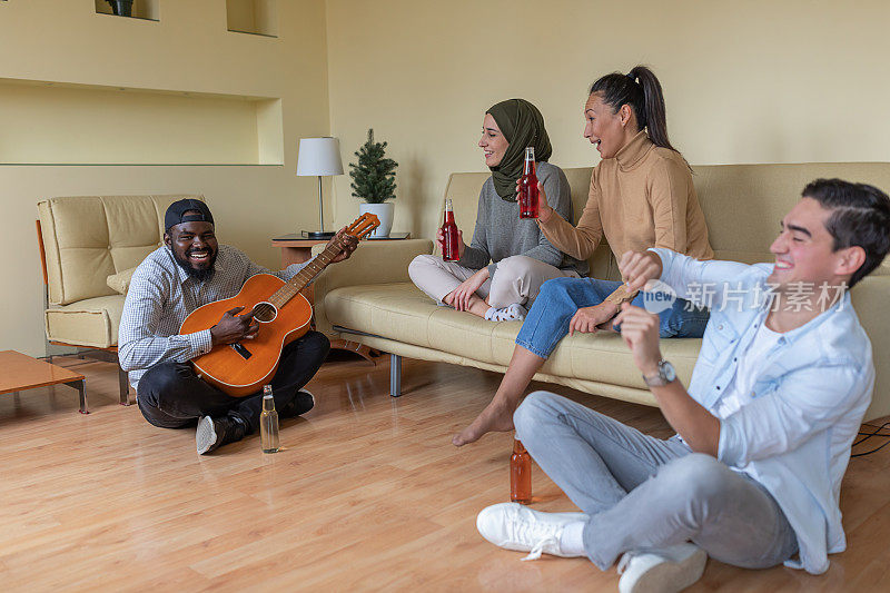 欢乐的多民族朋友群在现代公寓里放松，弹原声吉他。