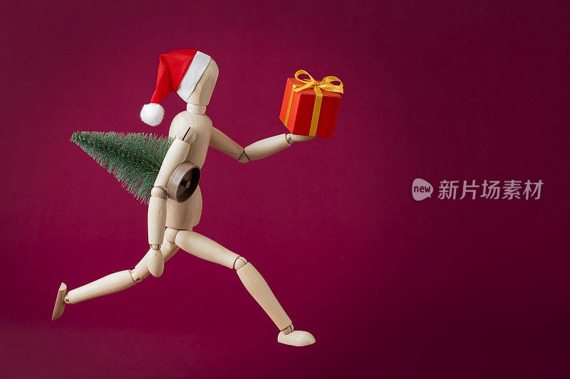 圣诞礼物-运行木制人体模型在圣诞老人的帽子手持一棵圣诞树和礼盒