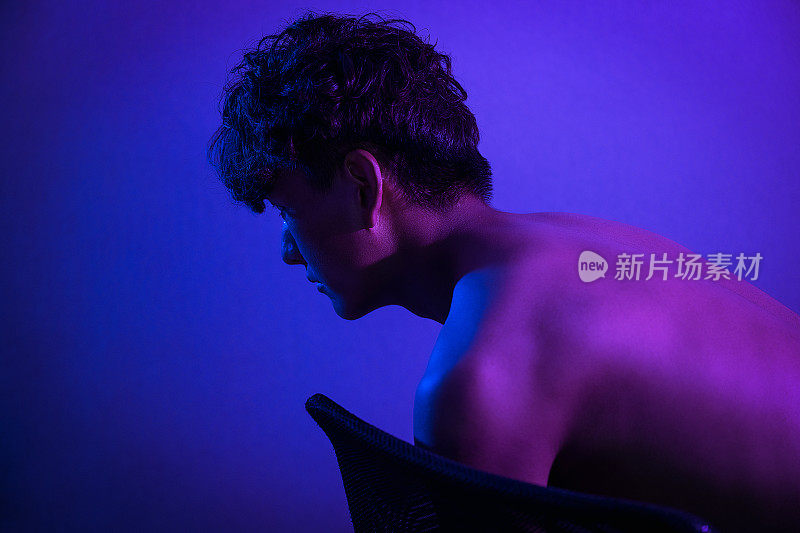 一个身强力壮的男人在紫光下裸露的肌肉
