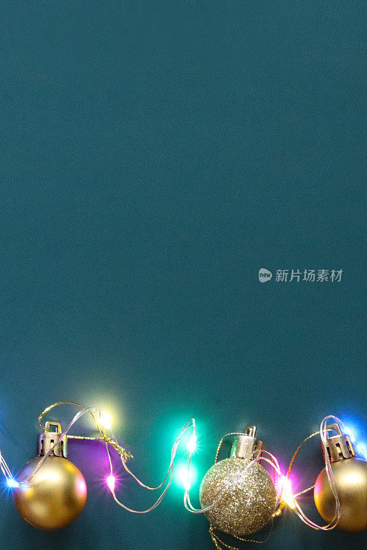 自制DIY简单的圣诞卡设计的形象与金色的小玩意和明亮的彩灯在青色的蓝色背景，手工节日圣诞贺卡复制空间