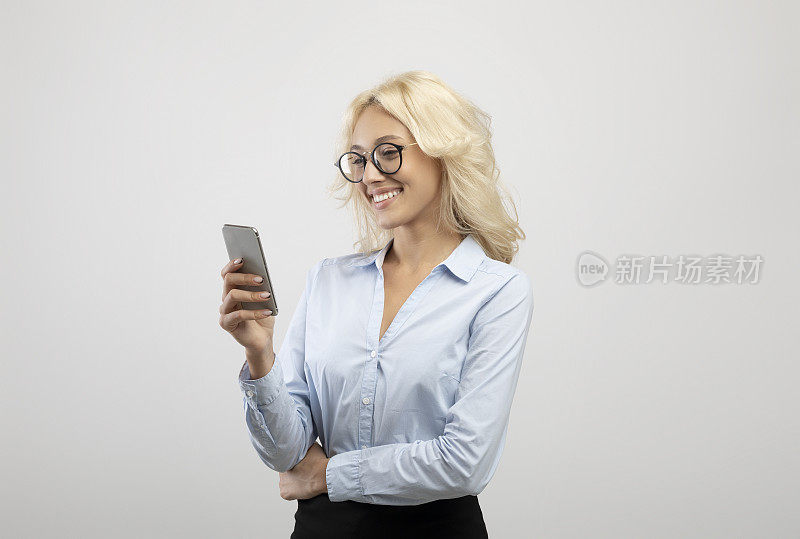 年轻女企业家的肖像与手机工作在线或与客户聊天在灯光工作室背景
