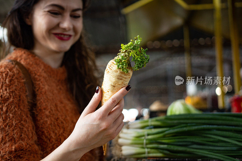 一名年轻女子在当地食品市场购买新鲜水果和蔬菜的照片