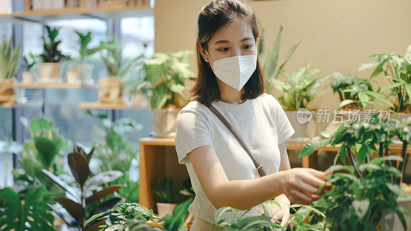年轻的亚洲女性穿着现代大地色调的布料选择植物种植园自然爱好者的生活方式在超市