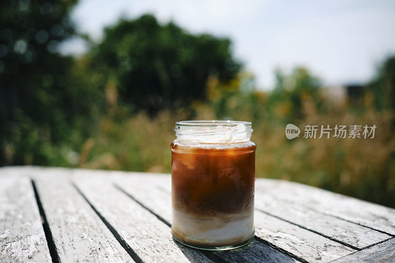 在一个炎热的夏日，破旧的花园桌子上放着冰拿铁。