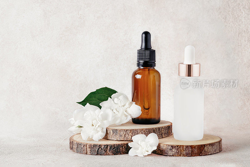 医疗和化妆品用的玻璃滴管瓶和木切上的茉莉花。水疗中心的概念。