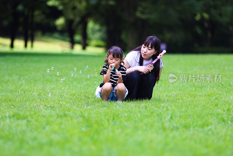 妈妈和女儿在公园里玩肥皂泡