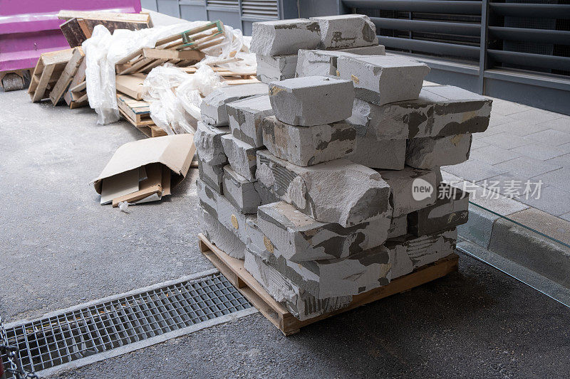 出口建筑垃圾碎片，残余的白色蒸压加气混凝土砖。纸板，保鲜膜和木制托盘背景上的垃圾容器。