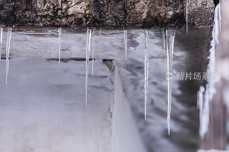 冰柱挂在屋顶上。冬天的背景。天气。气候。冰