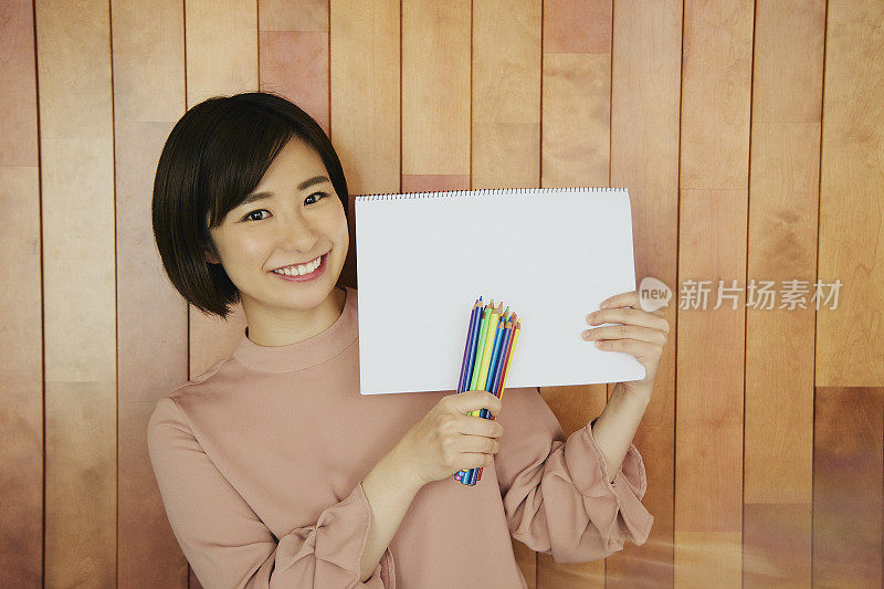 一个女人手里拿着一包彩色铅笔和速写本