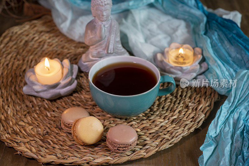 茶或咖啡在杯子里，马卡龙与佛和烛光-休息