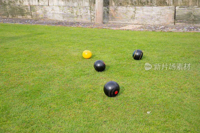 在一场比赛中，黑色的保龄球聚集在皇冠绿保龄球草地的黄色杰克周围，选手们的目标是最接近杰克，以赢得比赛