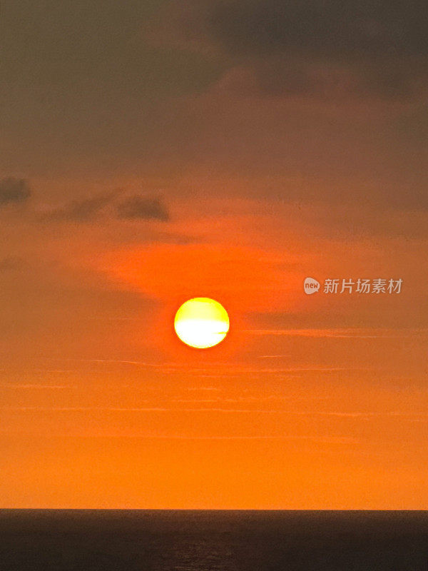 太阳在海上地平线上的橙色天空中落下的图像