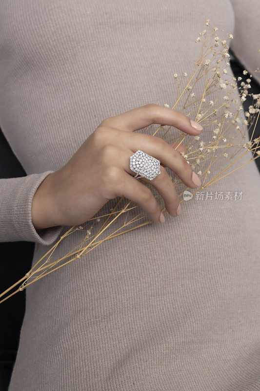 一个昂贵的白金刺绣戒指戴在女人的手指上。